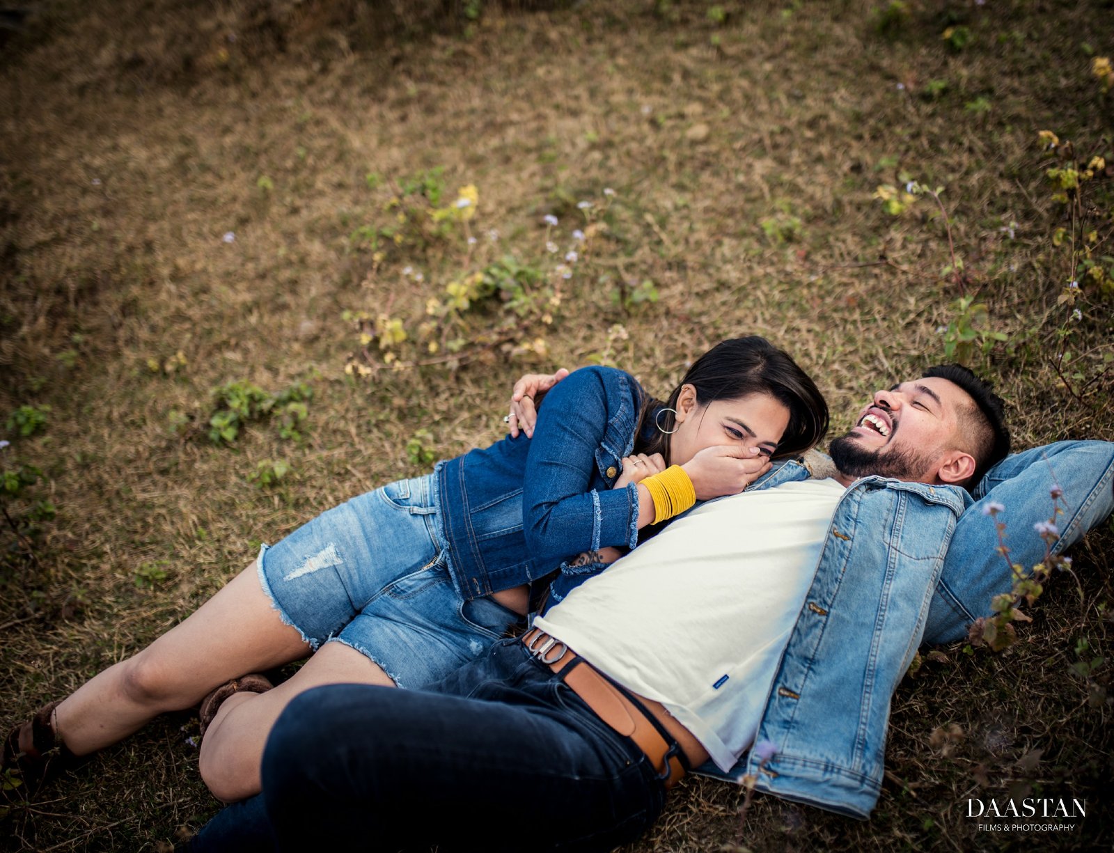 Couple lying on grass during outdoor pre-wedding shoot, candid Indian couple photography