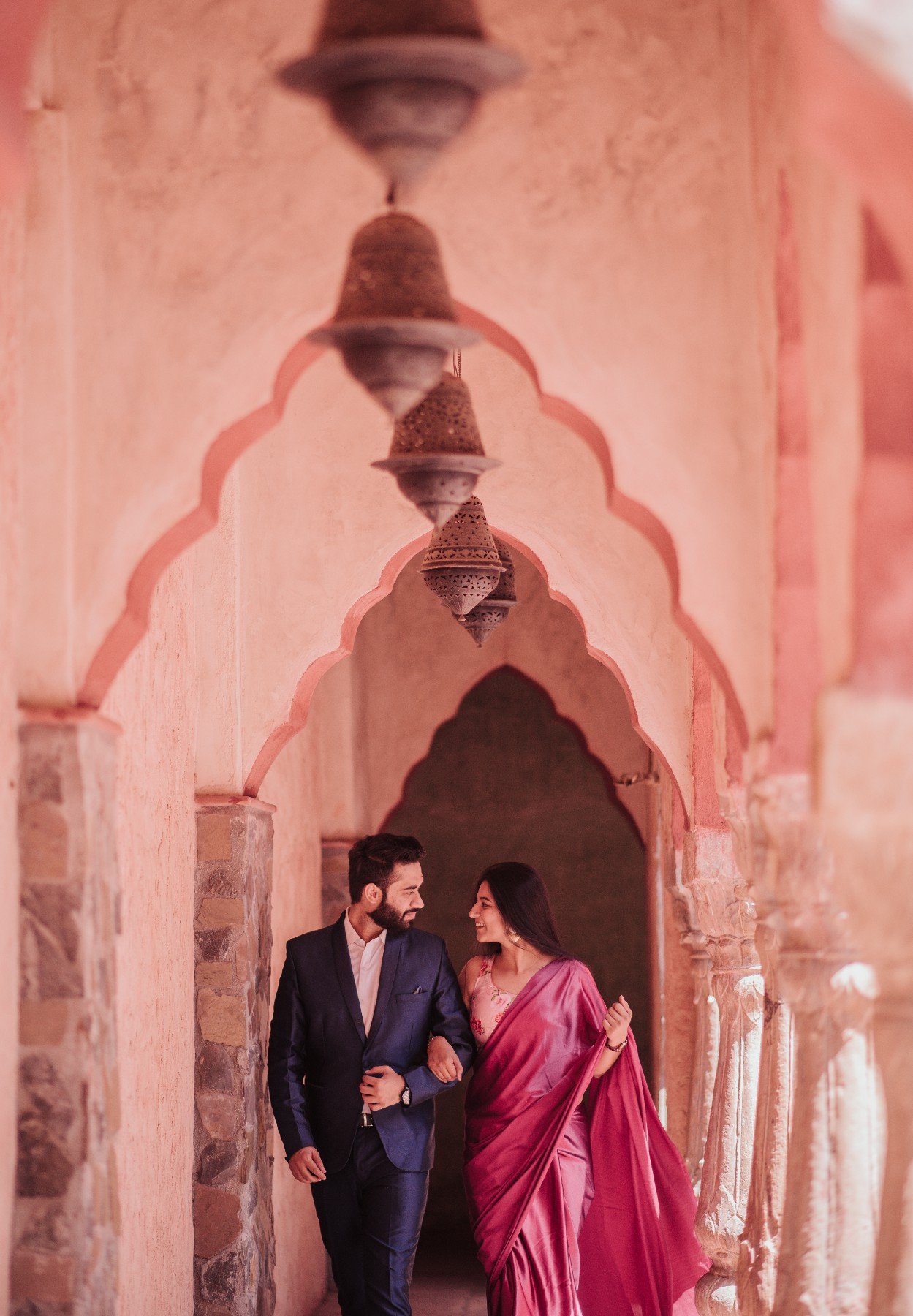Couple at pink Rajasthan arch during pre-wedding shoot, destination wedding photography India