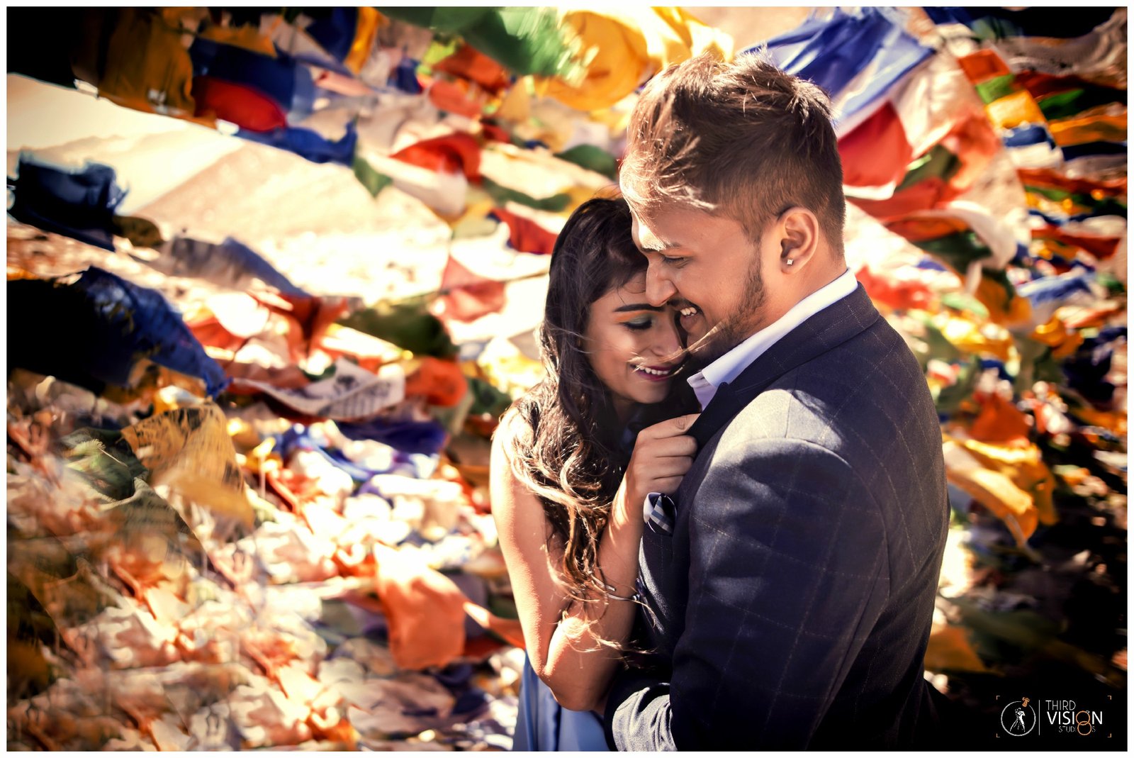 Romantic couple with Tibetan prayer flags during pre-wedding shoot, destination Indian photography