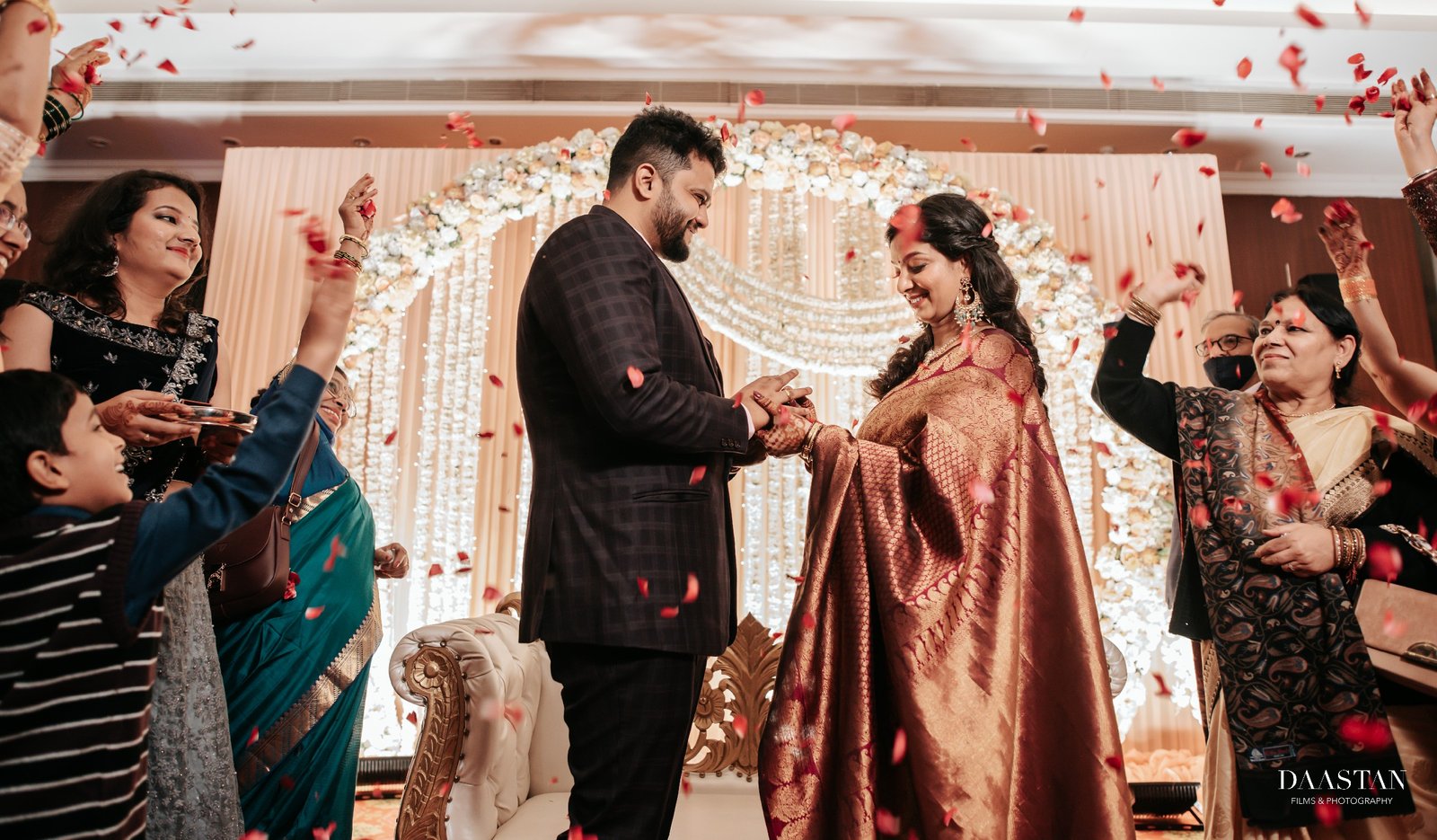 Couple on beautifully decorated wedding stage with floral backdrop, luxury Indian wedding photography